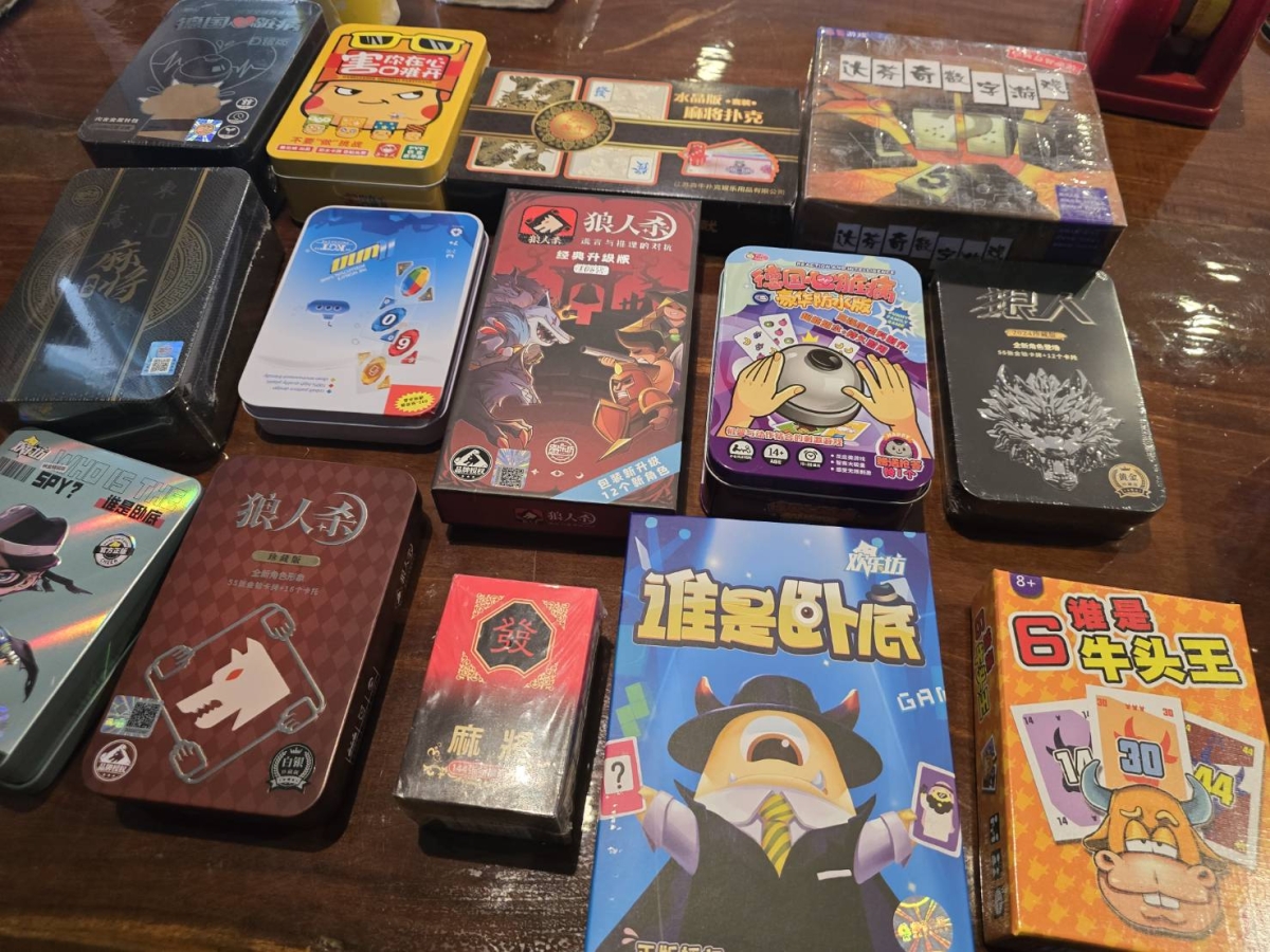 實際桌遊卡牌與遊戲盒擺放於桌面,可見狼人殺、誰是臥底等盒裝遊戲。